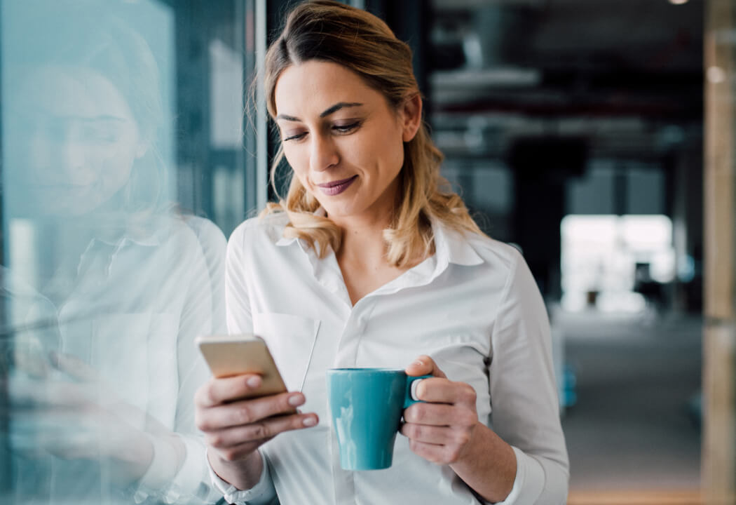 Business woman holding a coffee cup and smartphone